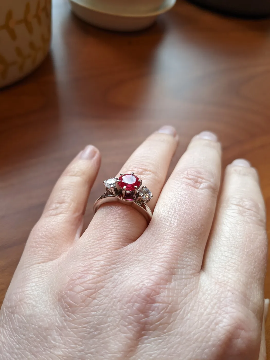Round ruby three-stone ring flanked by diamonds
