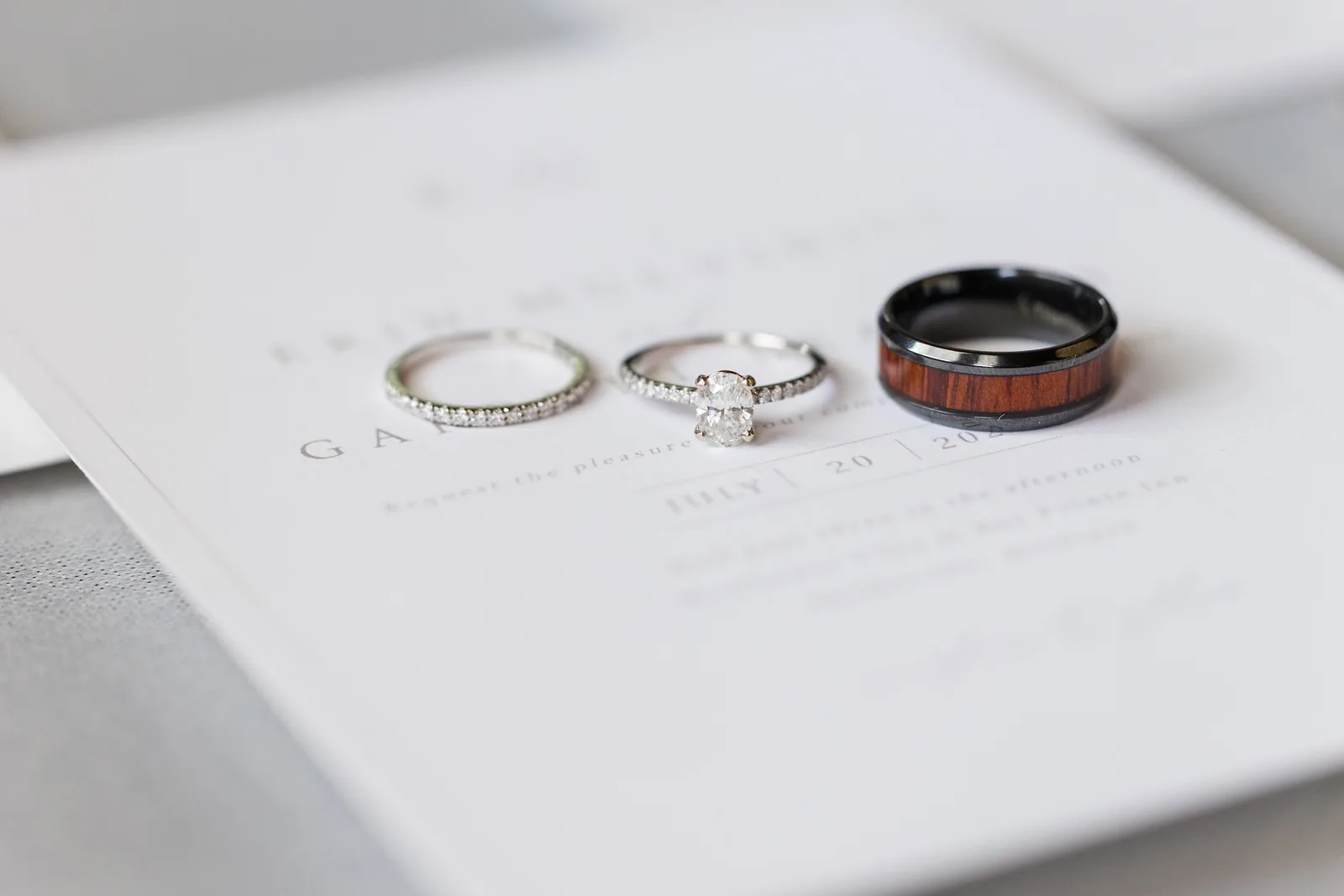 A wedding set — oval solitaire, diamond band, and a wood-inlay men's band